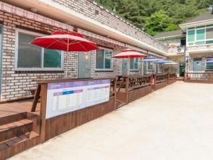 a patio with tables and umbrellas on a building at Inje Rainbow Pension in Inje