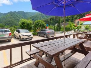a wooden picnic table with an umbrella on a deck at Inje Rainbow Pension in Inje