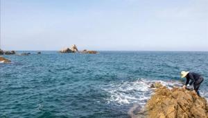 a man standing on a rock in the ocean at Samcheok Donghae Raeyo Pension in Samcheok