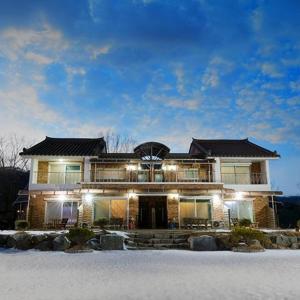 a large house with lights on in the snow at Yanggu Dandelion Pension in Yanggu