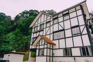 a white and black building with trees in the background at D Pine Villa in Bukit Tinggi