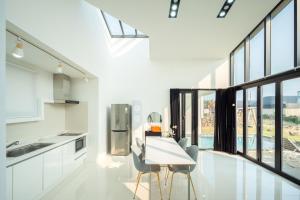a white kitchen with a table and chairs and windows at Daejung Secret Gennie Poolvilla in Seogwipo