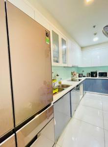 Il comprend une grande cuisine avec des placards blancs et un réfrigérateur. dans l'établissement Hana homestay- 1 Phòng ngủ trong căn hộ chủ nhà đang ở tại Park 4-Vinhome Central Park Tân cảng Bình Thạnh HCM- sát landmark 81, à Hô-Chi-Minh-Ville