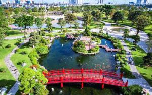 un pont rouge sur une rivière dans un parc dans l'établissement Hana homestay- 1 Phòng ngủ trong căn hộ chủ nhà đang ở tại Park 4-Vinhome Central Park Tân cảng Bình Thạnh HCM- sát landmark 81, à Hô-Chi-Minh-Ville