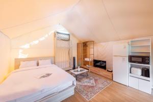 CheongdoにあるCheongdo Shinnanda Aegyeon Glampingのベッドルーム(白いベッド1台、冷蔵庫付)