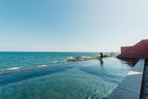 浦项Pohang Case Poolvilla的一名男子站在海边的无边泳池里