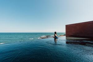 a woman sitting in the water next to the ocean at Pohang Case Poolvilla in Pohang