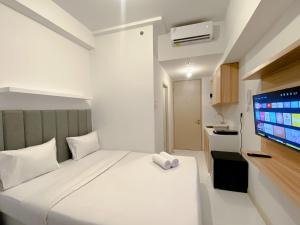 a bedroom with a white bed and a flat screen tv at Restful and Good Deal Studio at Tokyo Riverside PIK 2 Apartment By Travelio in Rawalembang