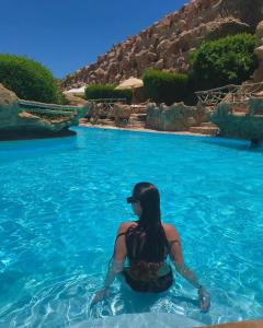 Caves Beach Resort Adults Only في الغردقة: وجود امرأة جالسة في الماء في المنتجع