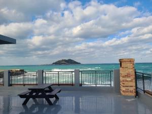a picnic table on a balcony overlooking the ocean at Jeju ongpo490 Pension in Jeju