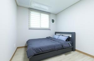 a bed in a white room with a window at Jeju ongpo490 Pension in Jeju