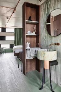 a bedroom with a bed and a desk and a mirror at Boutique Hotel Badhaus in Bressanone