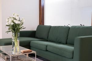 a green couch with a vase of flowers on a table at Stay Hyeopjae Soop in Jeju
