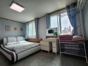 a bedroom with a bed and a desk and a window at Yeosu Daoljang Guesthouse in Yeosu