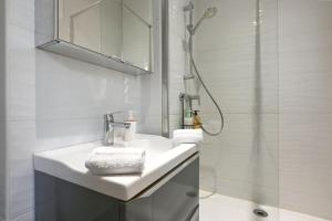 une salle de bain blanche avec un lavabo et une douche dans l'établissement Maison climatisée Gare à 10 min, idéale familles MaisonCarréeConciergerie, à Nîmes 23 autres photos