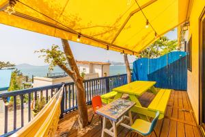 a table and chairs on a deck with a yellow umbrella at Namhae arahil pension in Namhae +19 photos