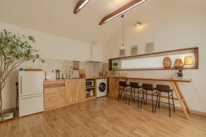 a kitchen with a white refrigerator and some bar stools at Jeju Cheongsu-ri Haru Private Pension in P'yŏnghwa-dong