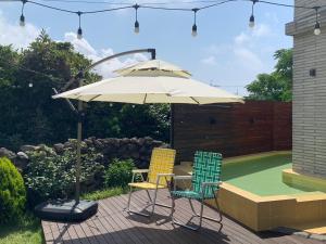 2 sillas y una sombrilla en el patio en Jeju Ianstay, en Jeju