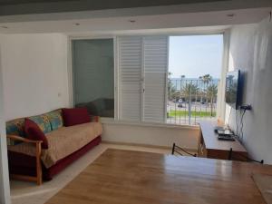 a living room with a couch and a table and a window at Sea view flat Deganya 60-8 in Qiryat H̱ayyim