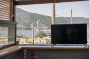 a window with a view of a city and a body of water at Geoje Yolo Guesthouse in Geoje