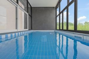 an indoor swimming pool with blue tiles and windows at Kyeongju JS Pet Poolvilla in Gyeongju