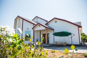 une maison blanche avec un banc et un parapluie dans l'établissement Jeju Woongine Pension, à Jeju