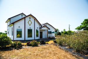 une petite maison blanche dans une cour ornée de plantes dans l'établissement Jeju Woongine Pension, à Jeju 4 autres photos