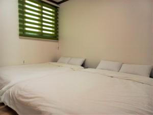 two white beds in a room with a window at Jirisan Bonjour Pension in Gurye +2 photos