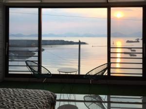 a bedroom with a view of the water with a table and chairs at Namhae Ocean Lounge Pension in Namhae