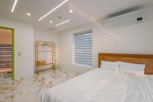 a bedroom with a white bed and a mirror at Namhae Boolgeun Noeul Pool Villa in Namhae