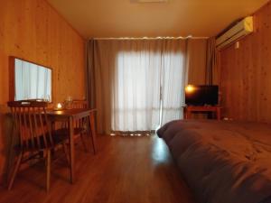 a bedroom with a bed and a table and a television at Jeju Viento Gimnyeong Pension in Jeju