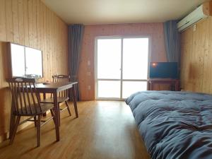 a bedroom with a table and chairs and a bed at Jeju Viento Gimnyeong Pension in Jeju