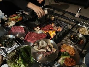 a table with different types of food on a grill at Namhae Staydan Pool Villa in Namhae