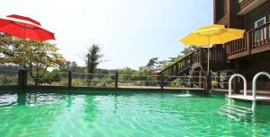 a swimming pool with an umbrella and a slide at Taean Anmyeondo Pension Marimo in Taean