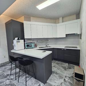 a kitchen with white cabinets and a counter with stools at Yeosu Bamview Stay in Yeosu