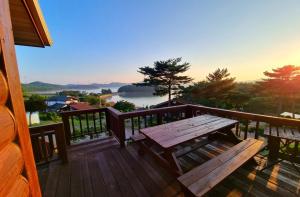 a wooden deck with a wooden bench on a balcony at Seosan Pine Sea Pension in Seosan
