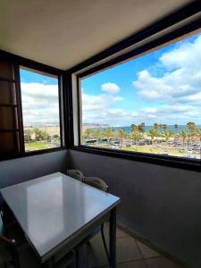 a table and two chairs in a room with two windows at Sea view panorama 62 in Haifa