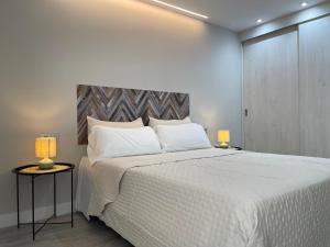 Un dormitorio con una gran cama blanca con dos lámparas. en Voix du Monde, en Tudela