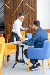 twee mannen zitten aan een tafel in een kamer bij RESIDENCE MH HOTEL in Laayoune