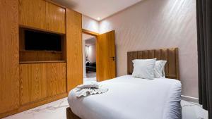 een slaapkamer met een groot wit bed en een televisie bij RESIDENCE MH HOTEL in Laayoune +51 foto's