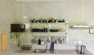 a kitchen with a sink and a shelf with pots and pans at Destination39 in Thalang