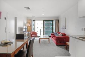 Una sala de estar con un sofá rojo y una mesa. en City Hideaway 1 BR Apt with Pool and Gym, en Auckland