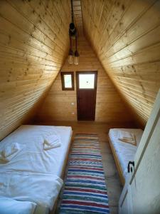 a bedroom with two beds in a wooden attic at La Fermă in Şeíca Mare