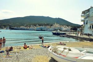 eine Gruppe von Menschen am Strand mit einem Boot in der Unterkunft Horta IV - Loft - Cadaqués in Cadaqués