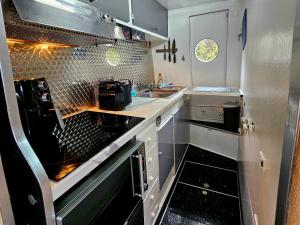 a small kitchen with white cabinets and black appliances at Rhapsody in Blue in Chertsey +17 photos