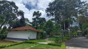 a small white building with a roof in a yard at Gavadana Resort Coorg in Madikeri
