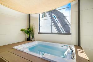 a bath tub in a room with a window at Urban Resort Villa ILILANI in Inbu