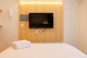 ein Schlafzimmer mit einem Bett mit Fernseher und einem Handtuch in der Unterkunft Modern Studio Room at Tokyo Riverside PIK 2 Apartment By Travelio in Rawalembang