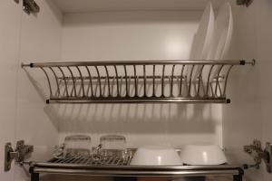 ein Küchenregal mit Gläsern und Geschirr darauf in der Unterkunft Modern Studio Room at Tokyo Riverside PIK 2 Apartment By Travelio in Rawalembang + 17 Fotos