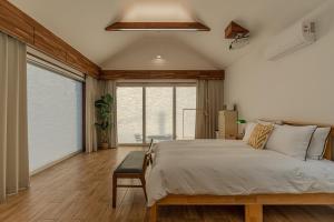 a bedroom with a large bed and a large window at Jeju Cheongsu-ri Haru Private Pension in P'yŏnghwa-dong